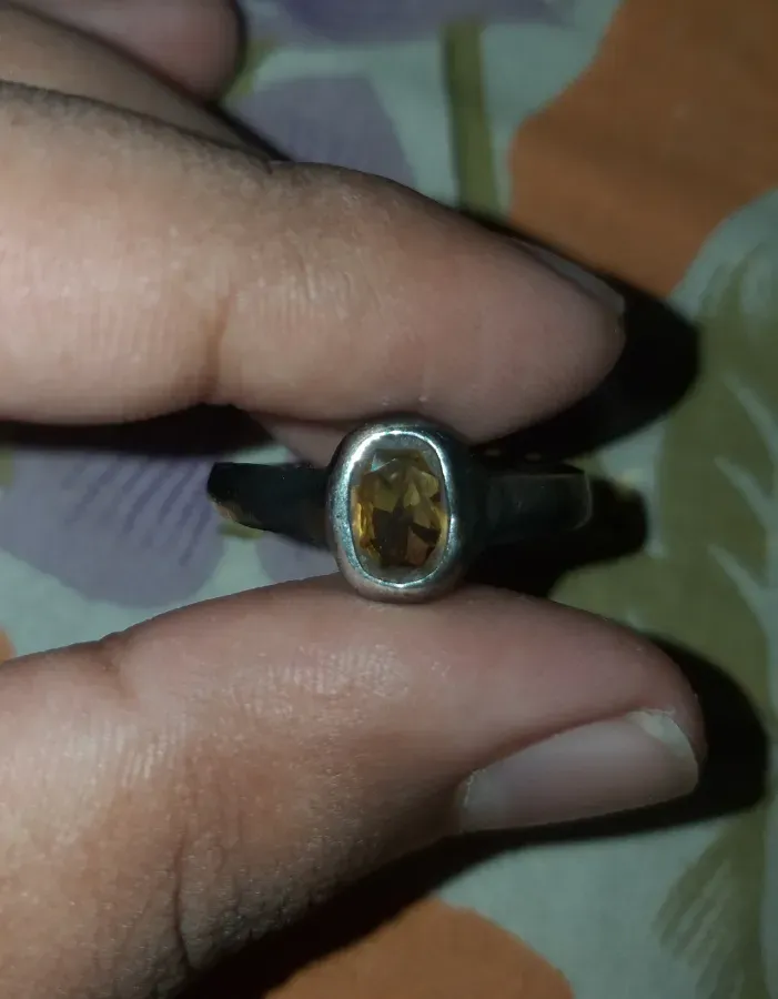 Yellow sapphire oval gemstone in a silver ring, photographed from a personal collection, in West Bengal, India, on November 30, 2023