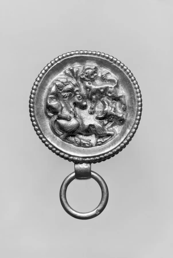 Colgante romano de oro en forma de caja redonda con relieve repujado de leones atacando a un toro, siglo I d. C.