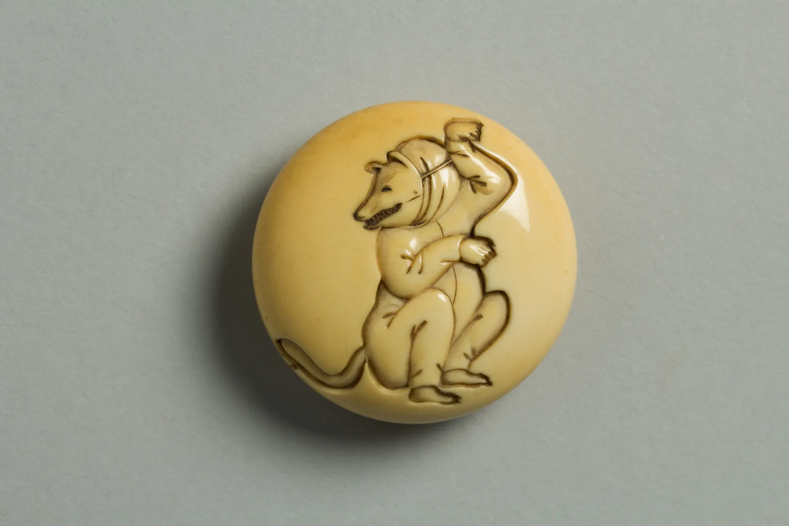 Netsuke circular de marfil con un actor caracterizado de zorro
