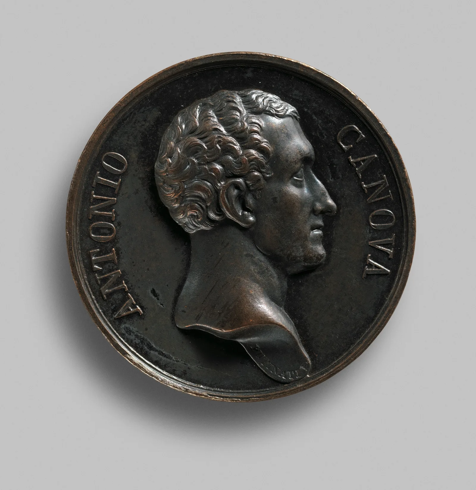 Medalla retrato de bronce con el perfil de un hombre, cara con relieve