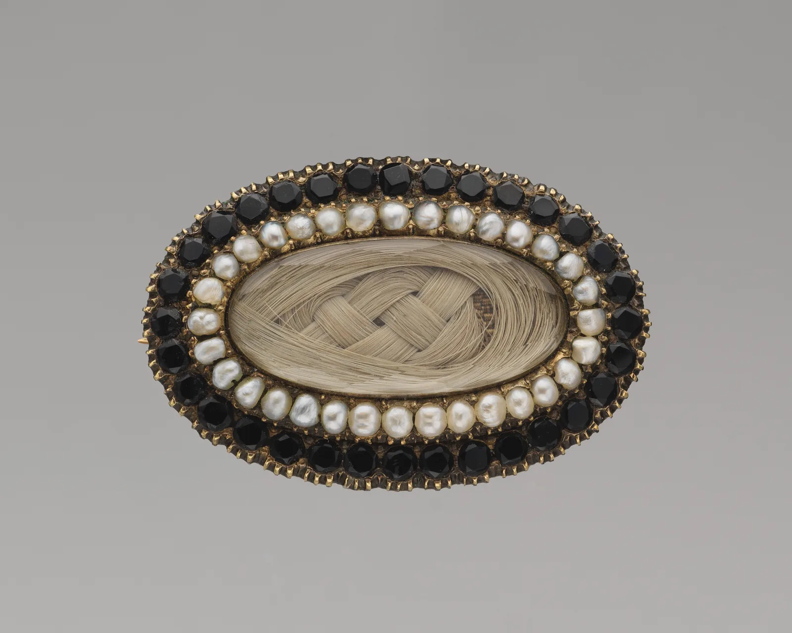 Broche conmemorativo de hacia 1850: azabache, perlas y cabello trenzado