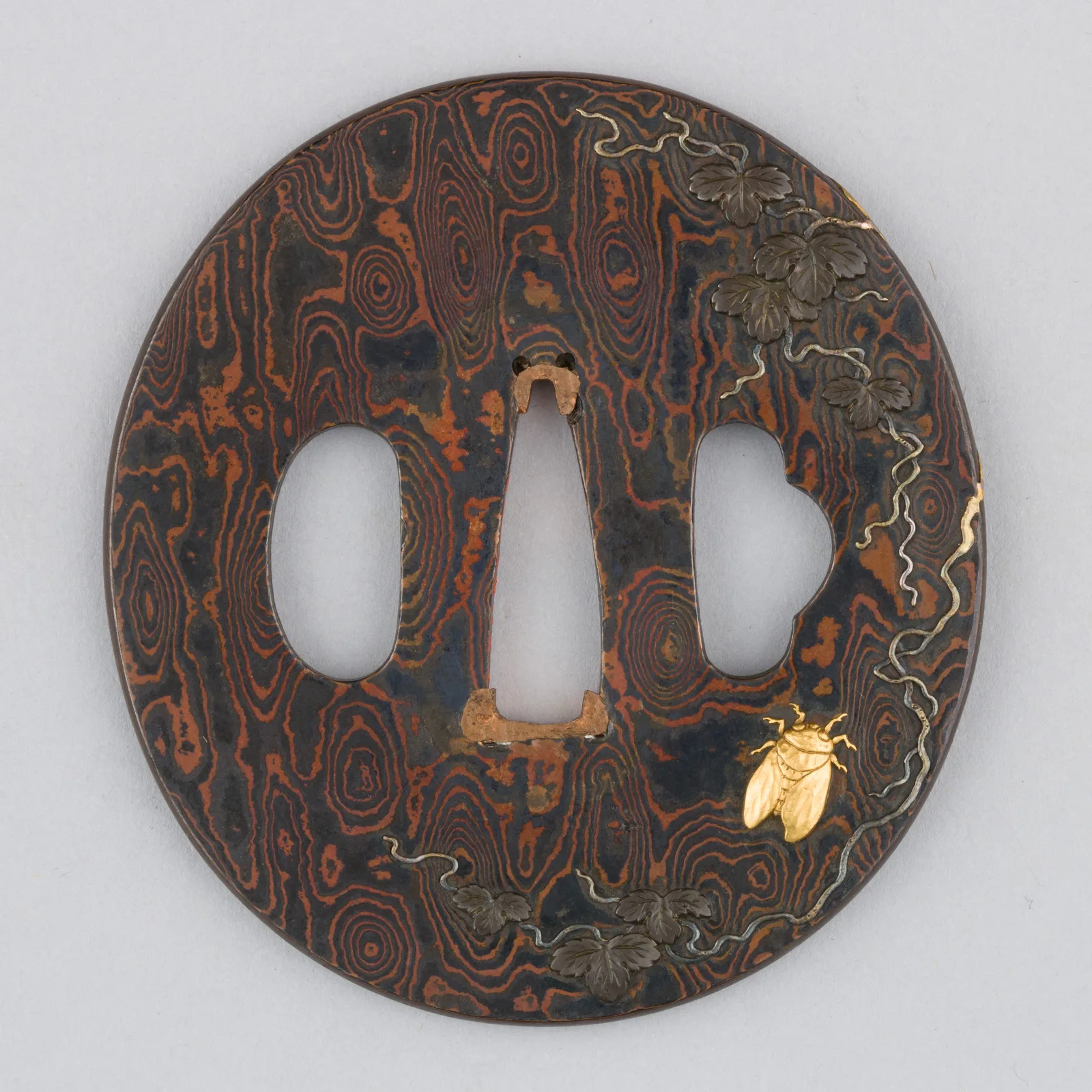 Tsuba de shakudo y cobre en técnica mokume-gane con pátina negra y detalles dorados