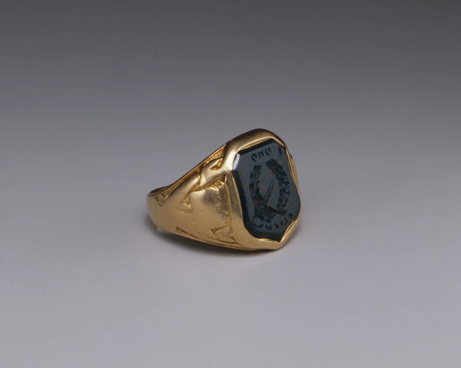 Anillo de sello de oro con una piedra intaglio oscura tallada en la cara plana