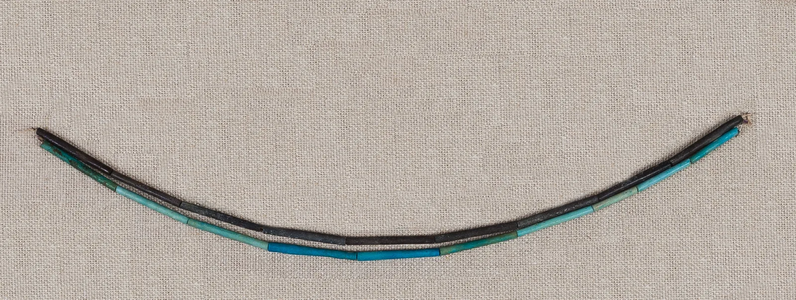 Collar egipcio de cuentas dispuesto en un arco suave que sigue la línea del cuello