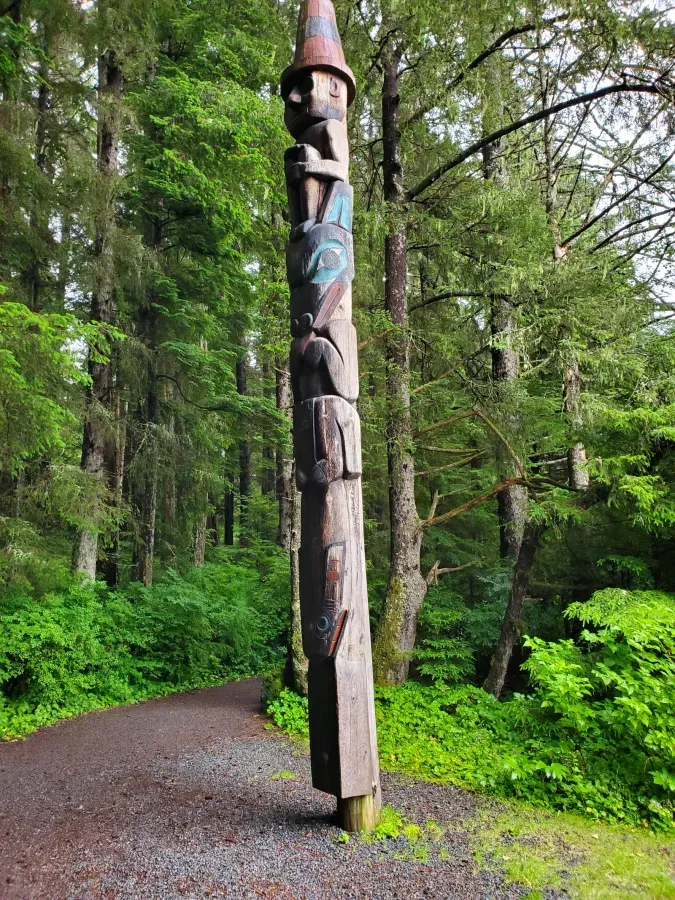 Tlingit Wolf Pole at Sitka National Historical Park, Alaska, carved figure of a wolf flanked by a fish and a human in a tall hat