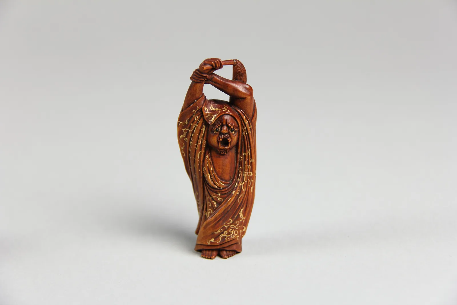 Netsuke de madera tallada con la figura del Daruma, adornado con oro